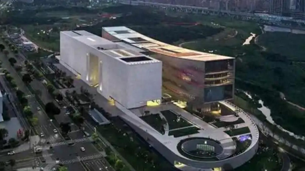 白色几何体块馆舍与弧形基座相融，屋顶绿植庭院错落层叠，展现现代公共文化建筑的未来感。